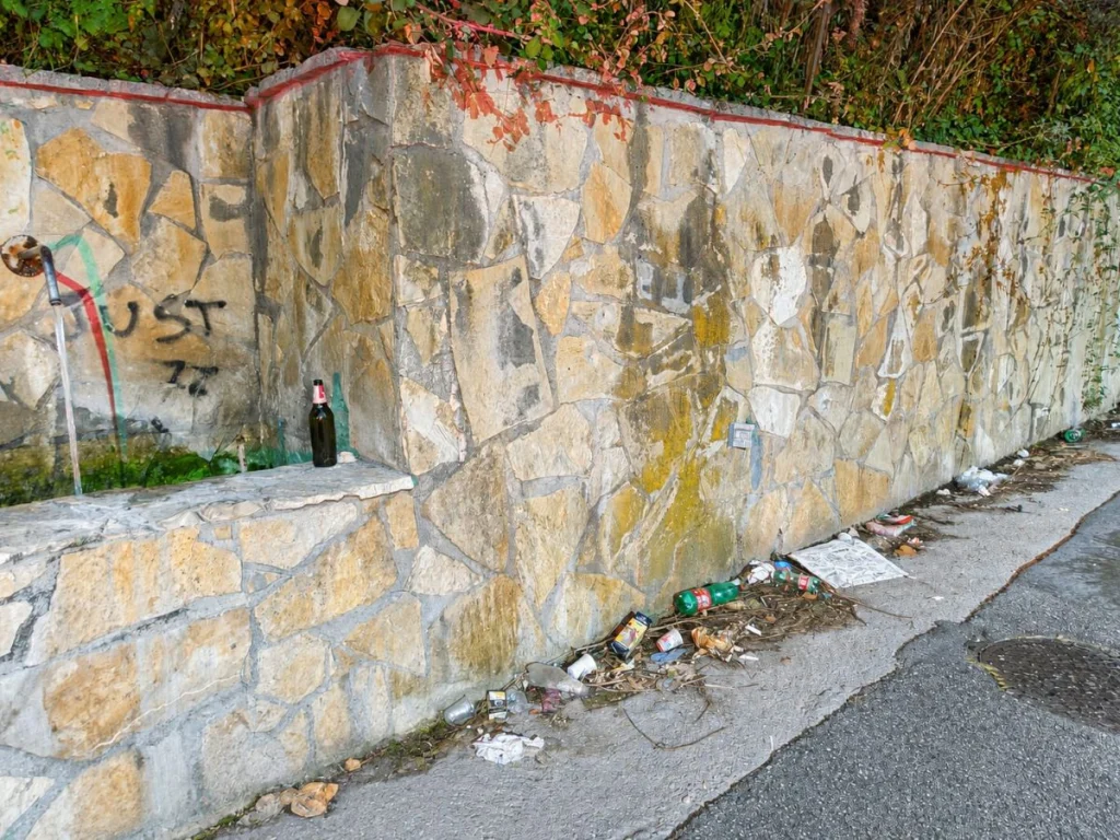Bottiglie abbandonate sul bordo della fontana e spazzatura a terra